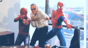 Stan Lee poserar med Spider-Man-statyer