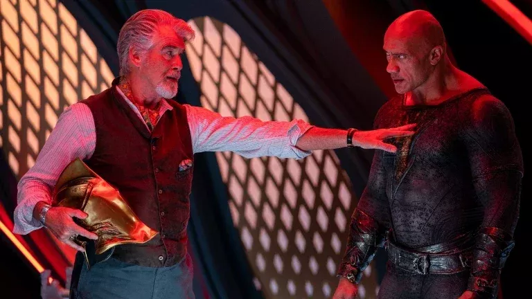   Pīrss Brosnans kā Dr Fate dalās ekrānā ar Dveinu Džonsonu kā Melno Ādamu.
