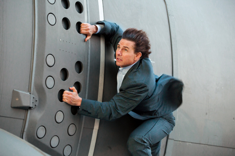   Tom Cruise, mint Ethan Hunt, aki egy repülőgépből lóg ki (Lehetetlen küldetés: Rouge Nation).